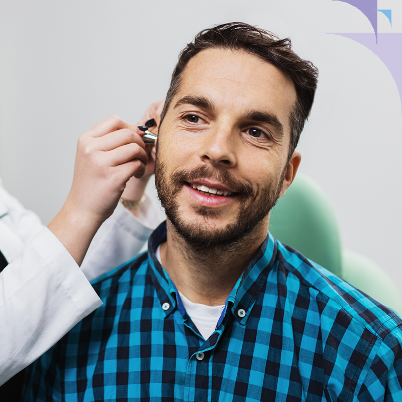 Man receiving an otoscopic ear exam from a hearing care professional to check for hearing health issues.