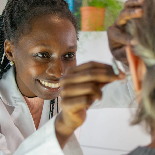 Smiling hearing care professional fitting a hearing aid on an adult patient during a hearing care appointment.