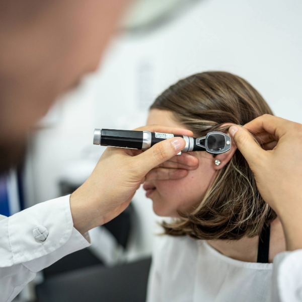 A hearing care professional examining a patient's ear with an otoscope during a hearing evaluation.